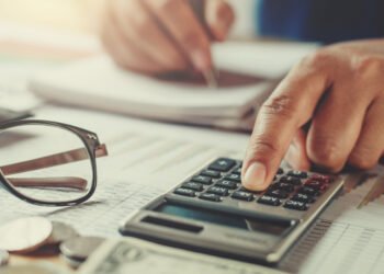 "Pessoa usando calculadora para organizar dívidas, ilustrando a dúvida sobre se a dívida caduca em cinco anos">