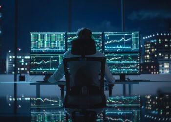 "Scalper trader operando à noite em frente a múltiplas telas com gráficos de mercado financeiro">